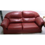 A contemporary maroon leather three seat sofa on wooden plinth base, approx width 200cm.