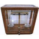 A cased set of chemical balance scales by Microid in glazed wooden cabinet, height 43cm.