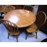 A round oak dining table on a pedestal base on tripod supports and four dining chairs with turned