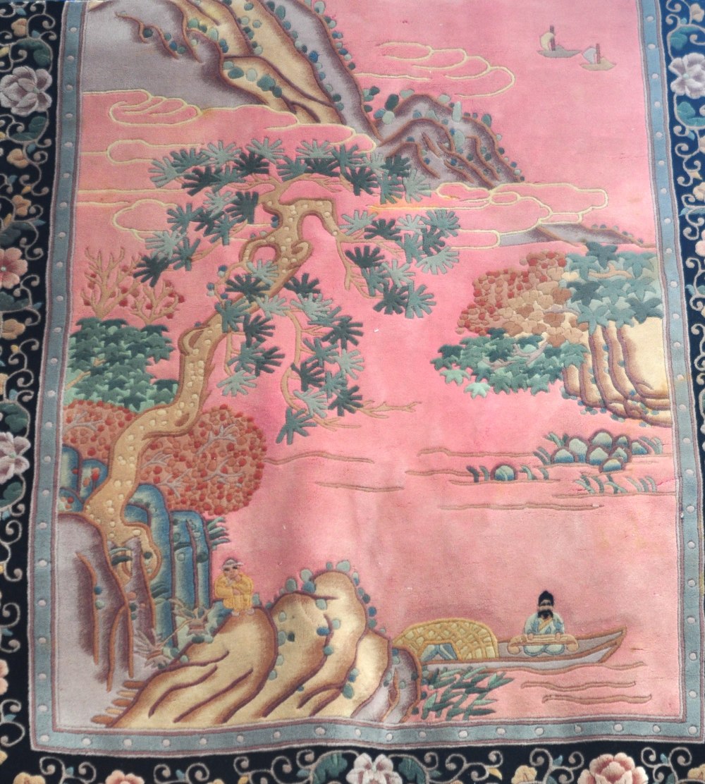 A rectangular pink ground Chinese wool rug decorated with Oriental scenes, 285 x 175cm.