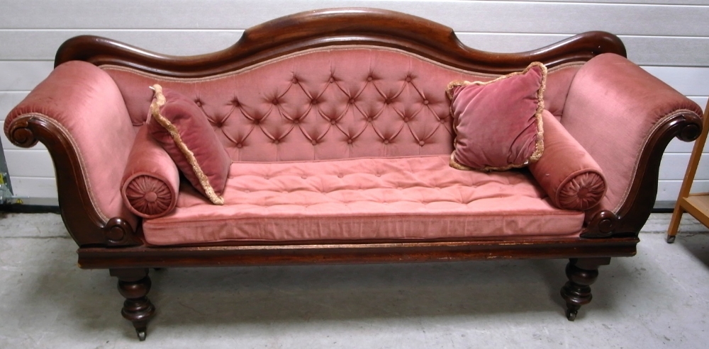 A Victorian walnut framed sofa with curving back and scrolling arms on cabriole legs and castors,