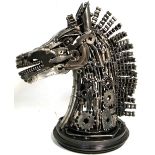 A modern metal sculpture of a horses head with articulated mane and manufactured from metal engine