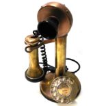 A vintage brass stick telephone.