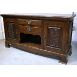 The base of an oak sideboard, two central drawers and aperture flanked by two carved drawers,