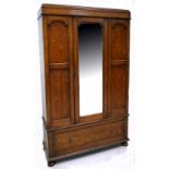 An early 20th century oak wardrobe, central glazed door with bevelled edge and one lower drawer,