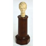 A late 19th century carved ivory head of a young gentleman, raised on turned rosewood stand to