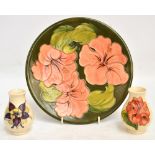 A Moorcroft plate in pink "Hibiscus" pattern on green ground with WM green painted signature to the