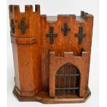 An unusual Edwardian oak stationery box modelled as a castle with hinged top above three division