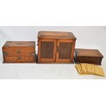 An early 20th century oak smoker's cabinet with hinged lid and two carved doors containing pipe