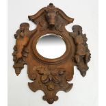 An early 20th century carved oak Black Forest style shaped hall mirror set with circular plate