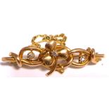 A yellow metal scroll brooch with a central shamrock set with white stones, approx weight 4.1g.