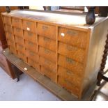 A 20th century oak pharmaceutical chest comprising twenty individual drawer units, length 122cm.