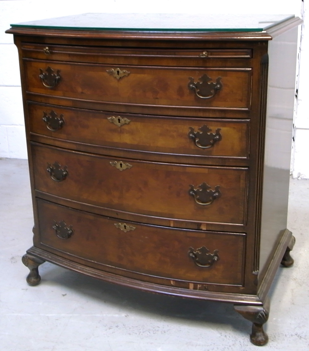 A bow front four drawer walnut chest of drawers of small proportions on shell knee carved squat