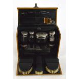 A pig leather domed travelling case containing chrome mounted glass jars, brushes, razor,
