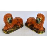 An opposing pair of late 19th century Staffordshire figures of recumbent lions on naturalistic