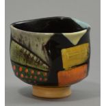 JOHN POLLEX (born 1941); a slipware footed cup of squashed form, richly patterned and painted,