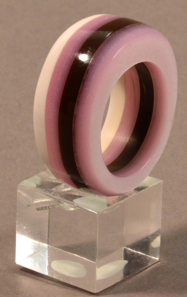 SARAH THIRLWELL; a chunky acrylic ring, purple, lilac and white, ring size R.

Provenance: Purchased