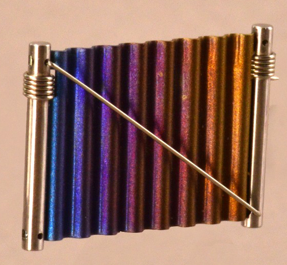 JOEL DEGEN (born 1944); a brooch, stainless steel and anodised aluminium, length 3.5cm.

Provenance: