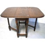 A mid 20th century oak drop leaf gate leg dining table on barley twist supports,