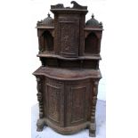 A 19th century Burmese hardwood bow front heavily carved cabinet decorated with musicians,