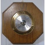 A brass ships barometer mounted on an oak octagonal base.
