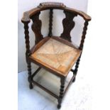 A early 20th century carved oak corner chair with rough seat.
