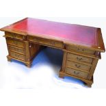 A reproduction partners desk with red leather top, brass handles,