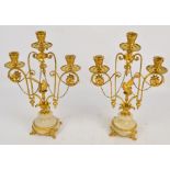 A pair of gilt metal candelabra, each with three sconces decorative with chains and opposing birds,