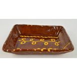 A 19th century earthenware rectangular slipware dish, 29 x 22.5cm. CONDITION REPORT: Minor losses to
