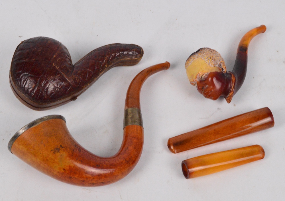 Two cased amber coloured cigar holders,