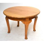 An early 20th century blonde oak oval extending wind-out dining table and two leaves with chunky