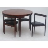 A 1960s teak extending circular dining table, and four chairs with triangular shaped seats, bar