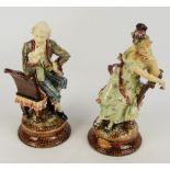 A pair of late 19th century German maiolica figures depicting a seated man and woman conversing,