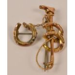 A 9ct gold brooch in the form of a riding crop and two horseshoes suspending a further horseshoe