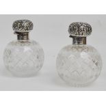 A near pair of hobnail cut glass and silver mounted perfume bottles with foliate embossed