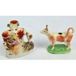 A Staffordshire cow creamer and a spill vase decorated with a woman milking a cow, height 16cm (both