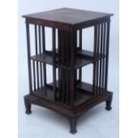 An Edwardian oak revolving square section bookcase raised on four section tapering corner supports,