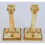 A pair of Royal Worcester blush ivory candlesticks modelled as Corinthian columns on spreading