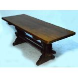 A Waring & Gillows oak refectory table raised on shaped end supports united by cross rails,
