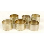 A set of four George VI hallmarked silver napkin rings with overall engine turned decoration and