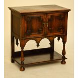 A 1920s oak side cabinet with moulded rectangular top above two doors, shaped apron,