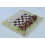 A small chess set in white and variegated onyx, height of king 4cm and an onyx board,