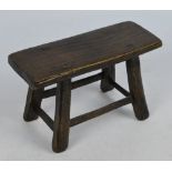 A small rustic oak stool/miniature table with stretchered supports, top 25 x 9cm, height 15cm.