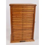 An oak dental cabinet in the form of a Wellington chest with twenty shallow drawers,