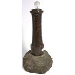 A polished Cornish stone table lamp in the form of a lighthouse on a rocky base, height 39cm.