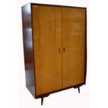 A retro 1960s twin door gentlemans wardrobe on tapering block supports with integral section for