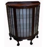 An early 20th century bow front display cabinet raised on ball and claw feet,