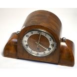 An Art Deco walnut mantel clock, silvered dial set with Arabic numerals.