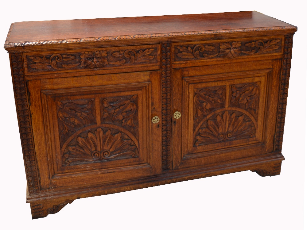 A 20th century oak carved sideboard, two drawers over two cupboard doors,