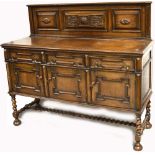 An early 20th century oak sideboard with carved oak panels above triple doors and cupboard sections